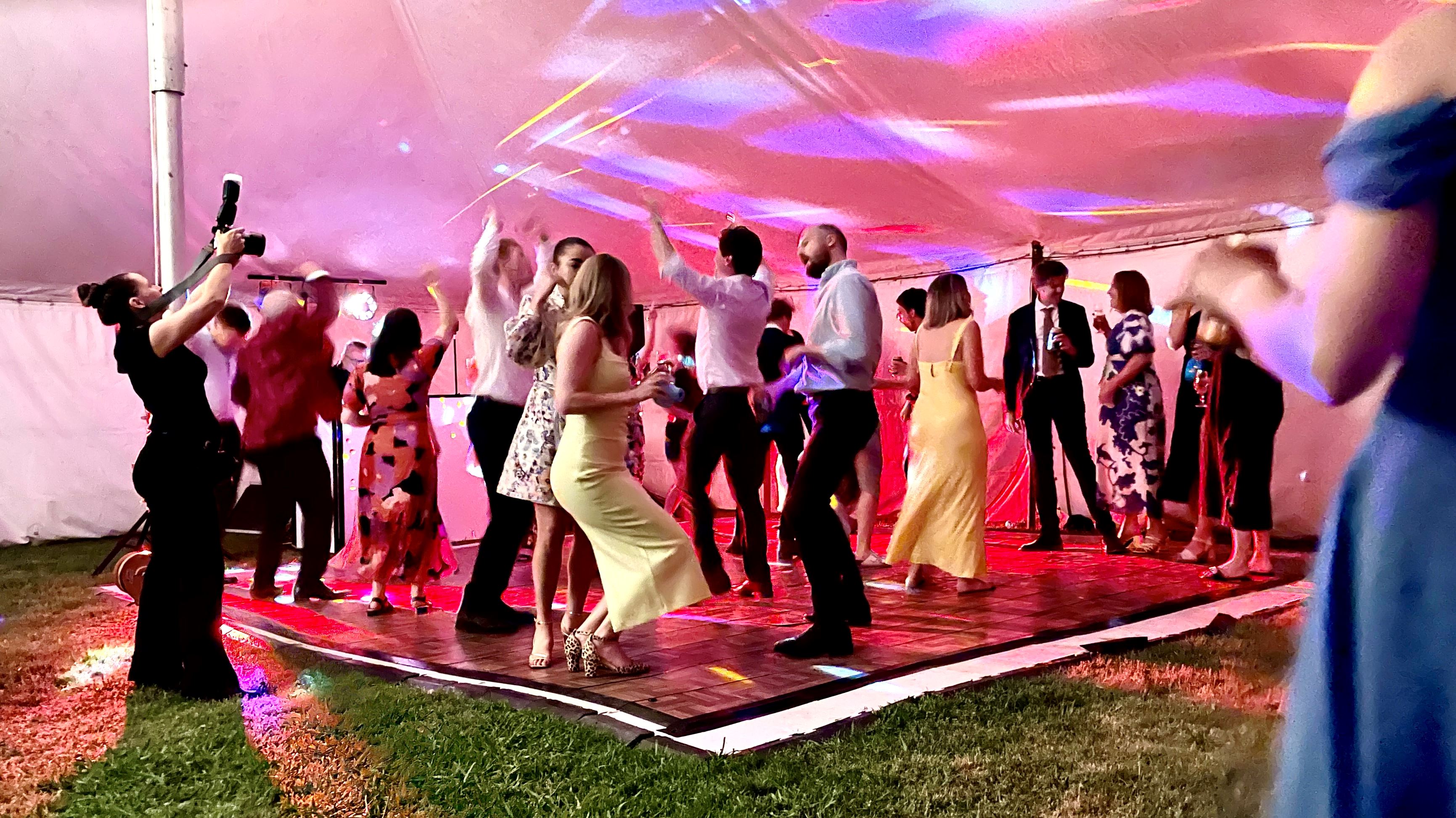 Packed dancefloor under marquee tent with coloured production lighting at Melbourne wedding